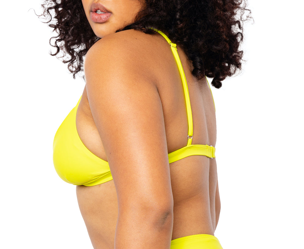 Model facing to the side wearing MIGA Ally Bikini Top in Lime Green with Adjustable Straps and Colette Bikini Bottom in Lime Green.