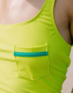 Model showcasing front pocket with emerald green detail of the lime green tankini top with scoop neck. 